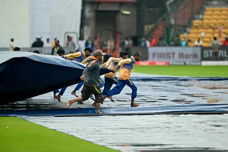 Groundsmen remove cover off the field at the start of the first day play of the first Test cricket match between India and New Zealand at the M. Chinnaswamy Stadium in Bengaluru on 16 October 2024.