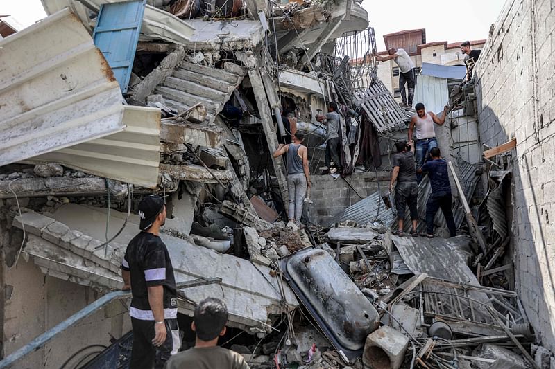 People gather outside a collapsed building as they attempt to extricate a man from underneath the rubble following Israeli bombardment in the Saftawi district in Jabalia in the northern Gaza Strip on 15 October 2024 amid the ongoing war in the Palestinian territory between Israel and Hamas