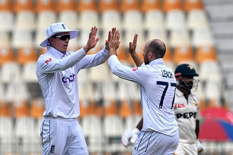 England's Jack Leach (C) celebrates with teammate after taking the wicket of Pakistan's Sajid Khan (R) during the second day of the second Test cricket match between Pakistan and England at the Multan Cricket Stadium in Multan on 16 October, 2024