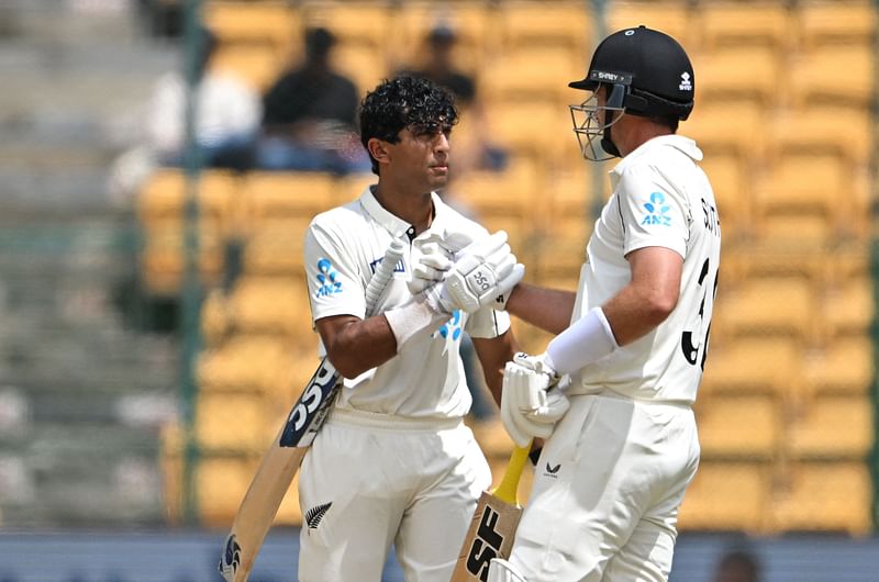 New Zealand's Rachin Ravindra (L) celebrates with his teammate Tim Southee after scoring a century during the third day of the first Test cricket match between India and New Zealand at the M Chinnaswamy Stadium in Bengaluru on 18 October, 2024.