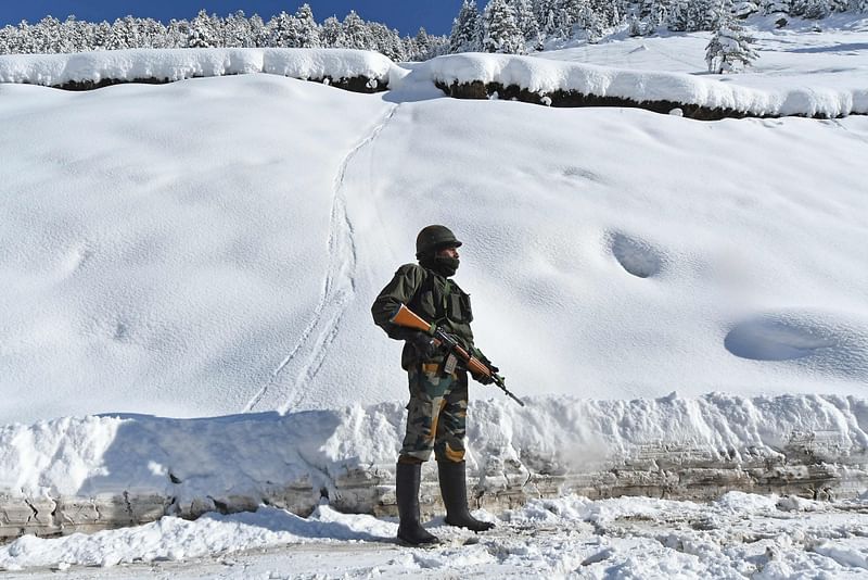 Indian army soldier stands on a snow-covered road near Zojila mountain pass that connects Srinagar to the union territory of Ladakh, bordering China on 28 February 2021