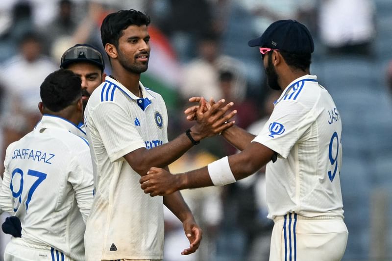 India's Washington Sundar celebrates with his teammate Jasprit Bumrah (R) after taking the wicket of New Zealand's Tim Southee during the first day of the second Test cricket match between India and New Zealand at the Maharashtra Cricket Association Stadium in Pune on October 24, 2024