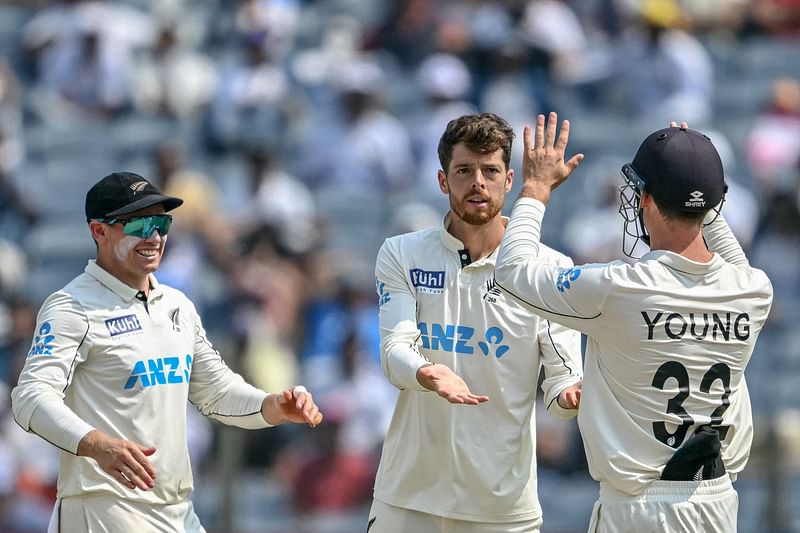 New Zealand's Mitchell Santner (C) celebrates with teammates after taking the wicket of India's Ravichandran Ashwin during the second day of the second Test cricket match between India and New Zealand at the Maharashtra Cricket Association Stadium in Pune on 25 October, 2024.