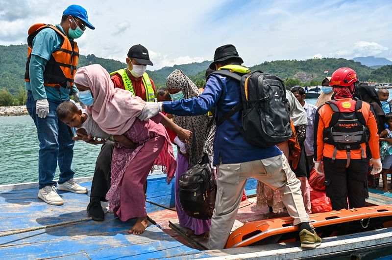 Search and rescue members evacuate Rohingya refugees from a boat after a week anchored ashore off the coast of Labuhan Haji in Southern Aceh province on 24 October 2024