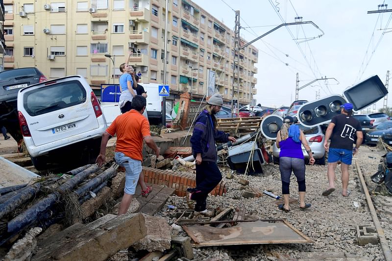 esidents walk next to piled up cars on railway tracks following deadly floods in Sedavi, south of Valencia, eastern Spain, on October 30, 2024. Floods triggered by torrential rains in Spain's eastern Valencia region has left at least 70 people dead, rescue services said on October 30.