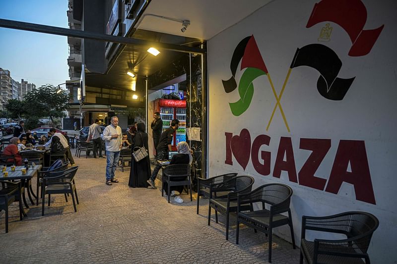 Palestinian restaurant-owner Bassem Abu Aoun speaks to a customer in front of establishment 'Hay Al-Rimal', named after his neighbourhood in Gaza City, in Cairo on October 28, 2024