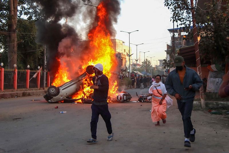 People run past burning vehicles of India's Bharatiya Janata Party (BJP) MLA during a protest to condemn the alleged killing of women and children in Imphal, capital of India's violence-hit northeastern state of Manipur on 16 November, 2024.