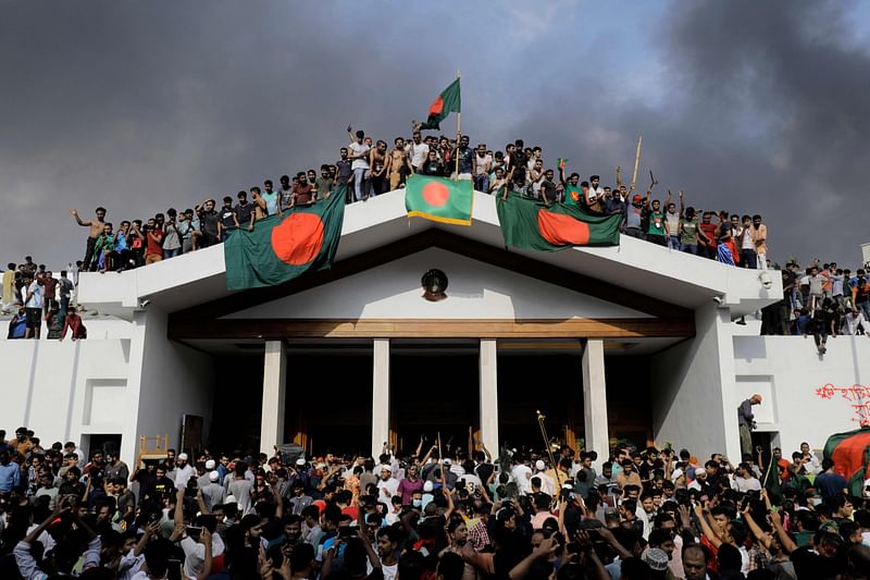 Anti-government protestors display Bangladesh’s national flag as they storm Prime Minister Sheikh Hasina’s palace in Dhaka on 5 August 2024