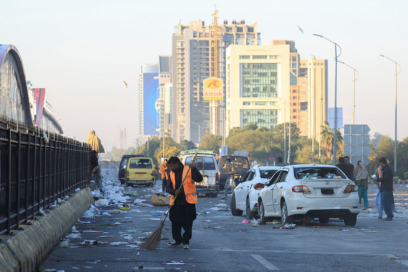 A worker clears the road, with damaged vehicles in the background, after security forces launched a raid on supporters of former Pakistani Prime Minister Imran Khan’s party Pakistan Tehreek-e-Insaf (PTI) who had stormed the capital demanding his release on Tuesday, in Islamabad, Pakistan, on 27 November 2024