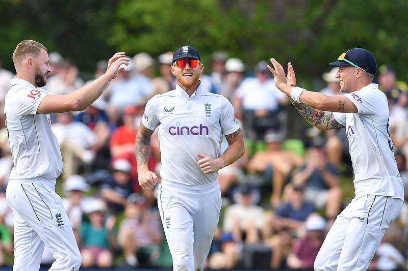 England's Gus Atkinson (L), Brydon Carse (R) and Ben Stokes celebrate the wicket of New Zealand's Kane Williamson during the first day of the first Test cricket match between New Zealand and England at Hagley Oval in Christchurch on 28 November, 2024