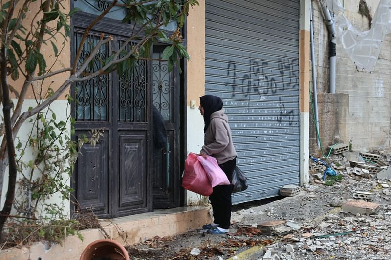 A resident who had fled the southern Lebanese border village of Shebaa, carries personal belongings upon her return following a ceasefire between Israel and Hezbollah took effect on 27 November 2024