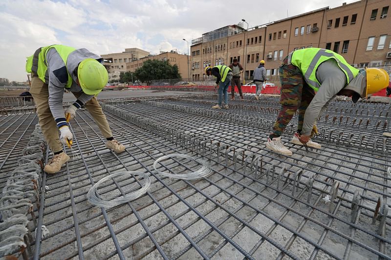 Iraqi labourers work on a bridge under construction on Abu Nawas Street in Baghdad on 26 November 2024.