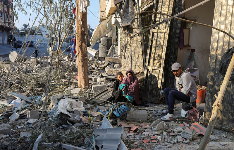 Palestinians sit amid rubble at the site of an Israeli strike on a house, amid the Israel-Hamas conflict, in Nuseirat in the central Gaza Strip 1 December 2024.