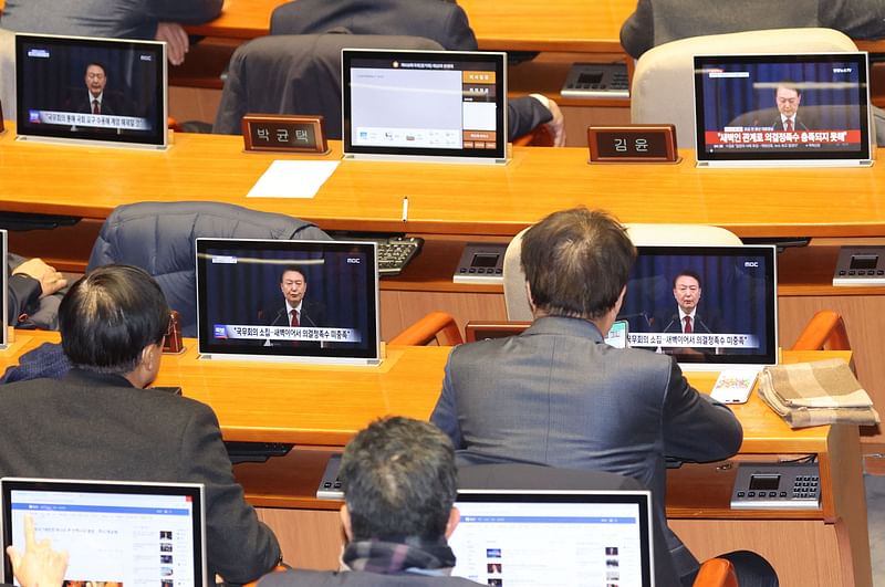 South Korean lawmakers watch screens showing a news broadcast of President Yoon Suk Yeol's speech on lifting martial law, at the main conference hall of the National Assembly in Seoul on December 4, 2024