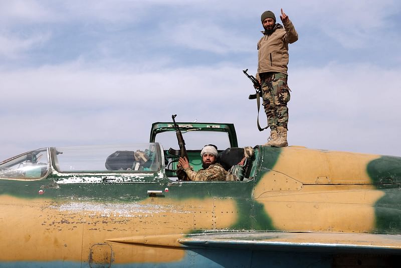 Anti government fighters gesture as they check a Syrian army jet after they took over a military airbase near the central city of Hama, on 6 December, 2024.