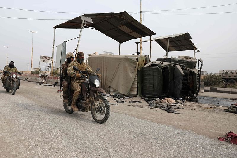 Anti government forces ride past a Syrian regime military vehicle overturned on the road, after rebel took control of the central Hama governorate, on December 7, 2024