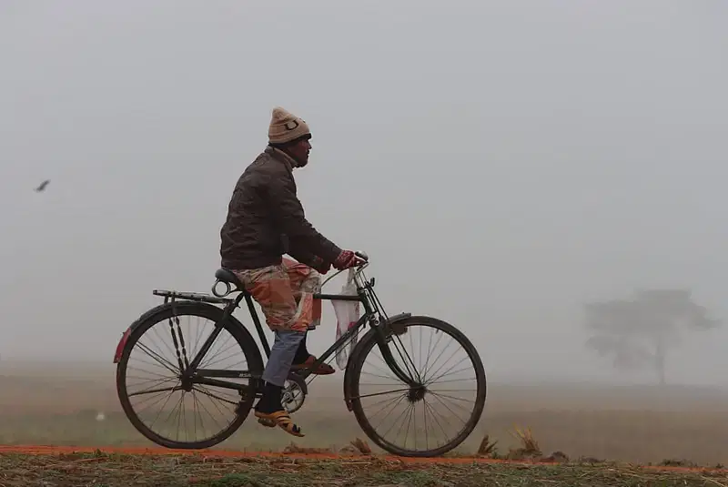 A man rides his bicycle as dense fog obstructs view. Photo taken from Chilarjhar area in Rangpur town