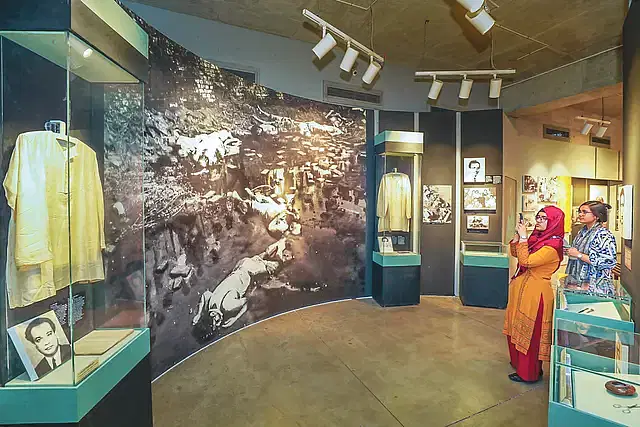 The Intellectuals' Corner of the Liberation War Museum. On the left is the Punjabi worn by martyr Dr. Alim Chowdhury. Next to it, a large photograph on the wall shows the mutilated bodies of intellectuals lying at the Rayerbazar mass killing site. Also displayed are the Punjabi of Professor Giyasuddin Ahmed and a photo of journalist Sirajuddin Hossain. Two young visitors, sisters, are observing the artifacts. This was taken last Wednesday.