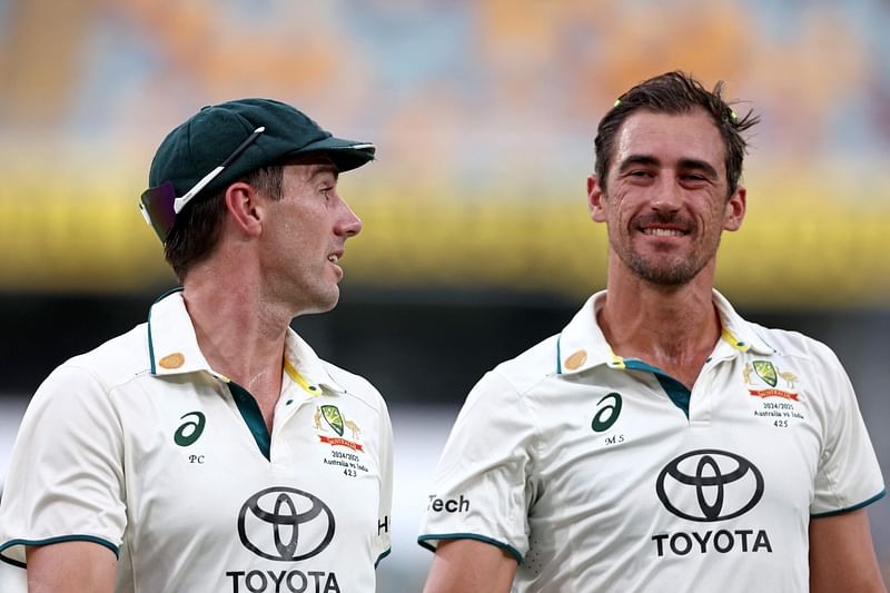 Australia’s captain Pat Cummins (L) talks with Mitchell Starc as they walk off the ground due to a rain delay on day five of the third cricket Test match between Australia and India at The Gabba in Brisbane on 18 December 2024