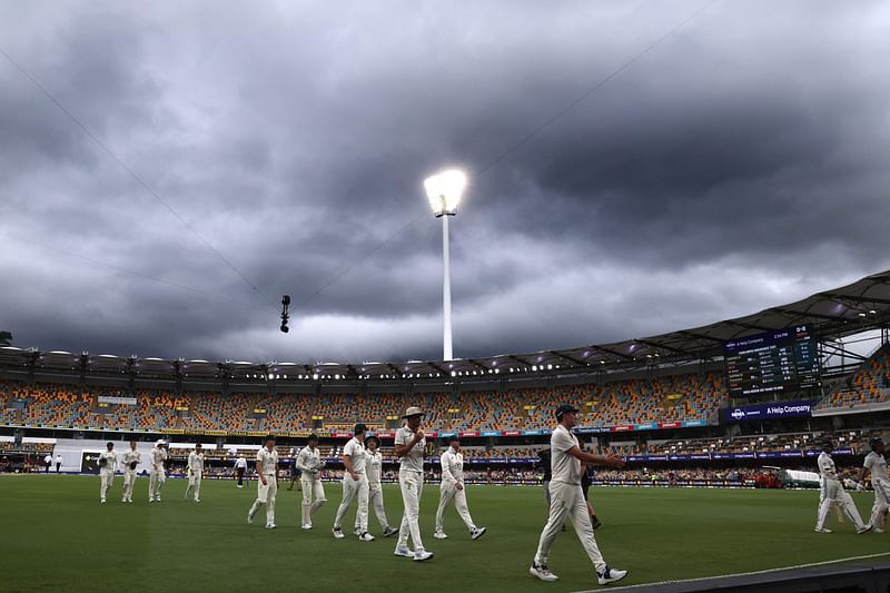 Australia’s captain Pat Cummins (C) leads his team off the ground due to a rain delay on day five of the third cricket Test match between Australia and India at The Gabba in Brisbane on 18 December 2024