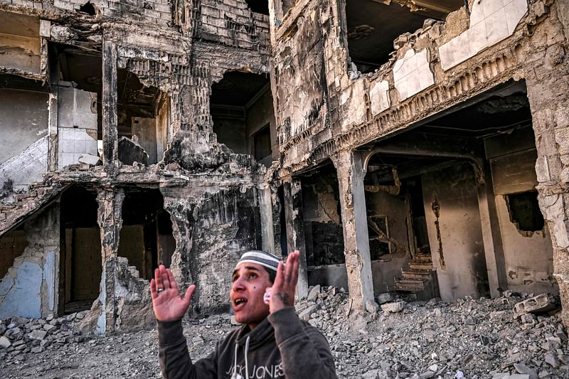 Mahmud Khaled Ajaj, 30, reacts while standing before a destroyed apartment building in the Yarmuk camp for Palestinian refugees south of Damascus on 19 December, 2024.