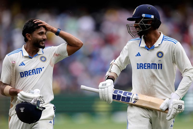 India's Nitish Kumar Reddy (L) and Washington Sundar leave the pitch during a rain delay on the third day of the fourth cricket Test match between Australia and India at the Melbourne Cricket Ground (MCG) in Melbourne on 28 December, 2024