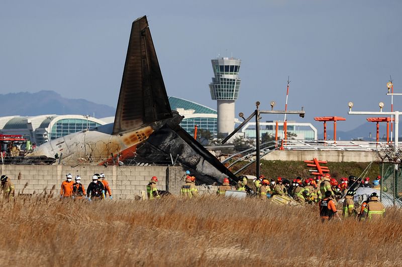 Rescue personnel are seen near the tail section of a Jeju Air Boeing 737-800 series aircraft after the plane crashed and burst into flames at Muan International Airport in South Jeolla Province, some 288 kilometres southwest of Seoul on 29 December, 2024.