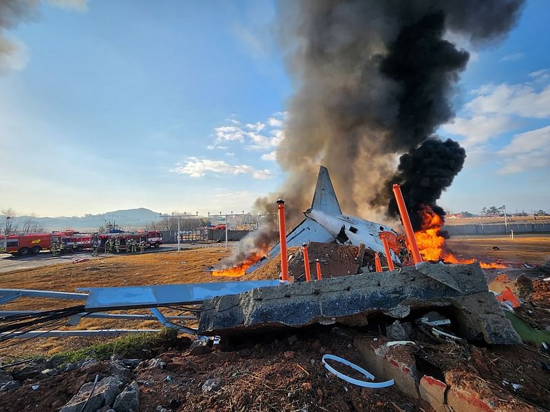 fire and smoke rise from the tail section of a Jeju Air Boeing 737-800 series aircraft after the plane crashed and burst into flames at Muan International Airport in South Jeolla Province, some 288 kilometres southwest of Seoul on 29 December, 2024.