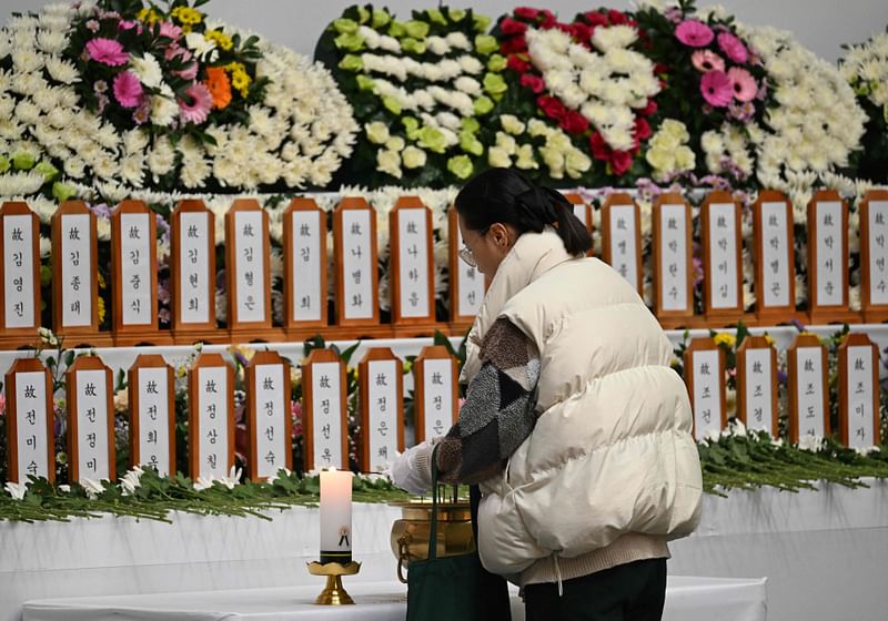 A mourner pays her respects at a memorial altar for victims of the Jeju Air plane crash, at Muan Sports Park in Muan on 30 December, 2024.