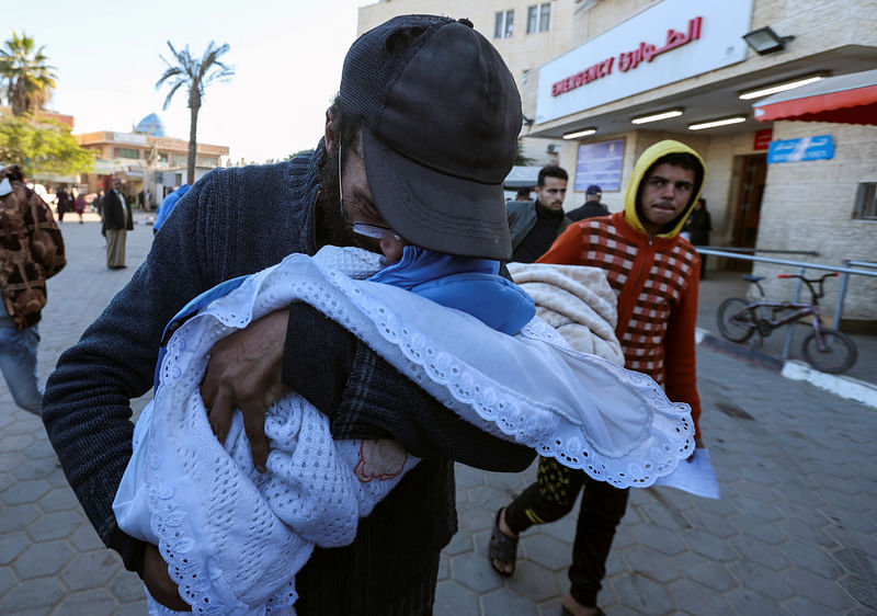 Yahya Al-Batran, the father of Palestinian infant Jumaa Al-Batran, who died of hypothermia after living in a tent with his displaced family, reacts as he embraces his body at Al-Aqsa Martyrs Hospital, in Deir Al-Balah in the central Gaza Strip, on 29 December 2024