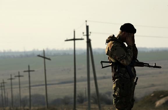 A Ukrainian soldier stands guard outside a Ukrainian Army military camp set up on a field close to the Russian border in east Ukraine