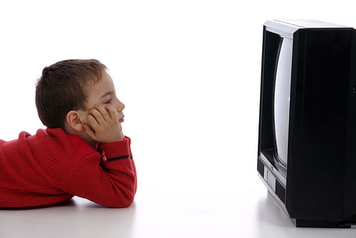 A kid is watching TV. Researchers say bedtime TV watching reduces the amount of sleep in them.