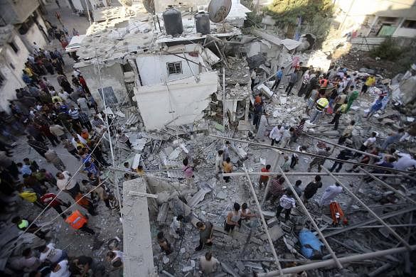 Rescue workers search for victims as Palestinians gather around the wreckage of a house, which witnesses said was destroyed in an Israeli air strike that killed at least nine members from the al-Ghol family, in Rafah in the southern Gaza Strip.