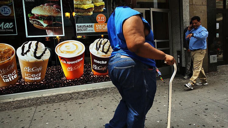 A woman walks by a sign advertising sugary drinks in a Brooklyn neighborhood with a high rate of obesity and diabetes on 11 June 2013 in New York City