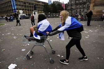 Pro-independence supporters push each other in a shopping trolley in Glasgow, Scotland, on September 19, 2014, following a defeat in the referendum on Scottish independence.