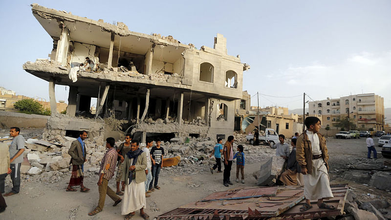 People stand at the site of an air strike in Sanaa 26 April, 2015. Air raids, naval shelling and ground fighting shook Yemen on Sunday in some of the most widespread combat since a Saudi-led alliance intervened last month against Iranian-allied Houthi militia who have seized wide areas of the country.