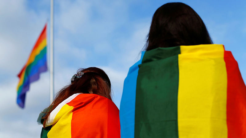 Mourners gather under a LGBT pride flag flying at half-mast for a candlelight vigil in remembrance for mass shooting victims in Orlando, from San Diego, California. Photo : Reuters