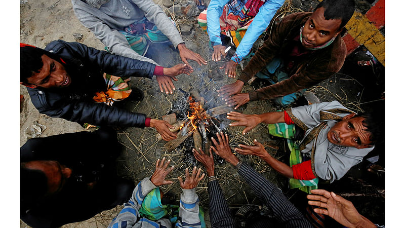 People light a fire in the street on a winter morning in Dhaka, Bangladesh