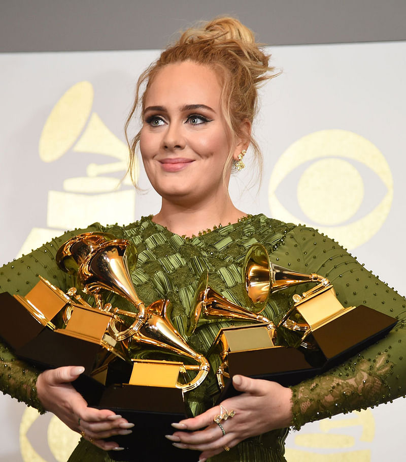 Adele poses in the press room with her trophies, including the top two Grammys of Album and Record of the Year for her blockbuster hit `Hello` and the album `25`, during the 59th Annual Grammy music Awards on February 12, 2017, in Los Angeles, California. AFP