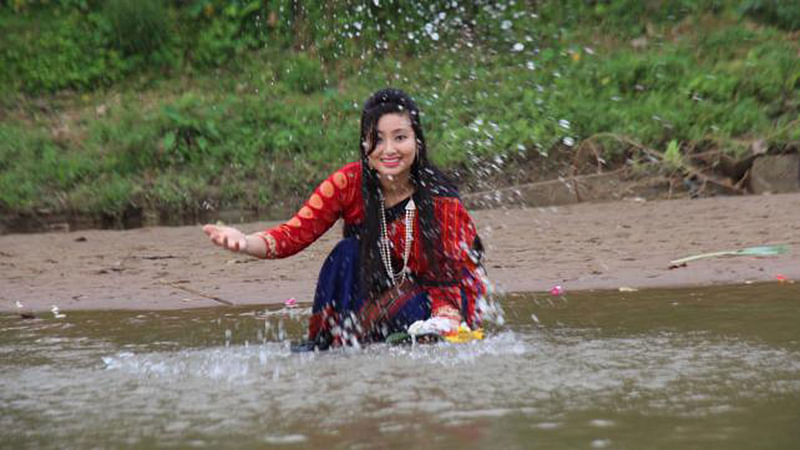 A young ethnic girl celebrates ‘Baishabi’ festival splashing in a water body in Khagrachari.