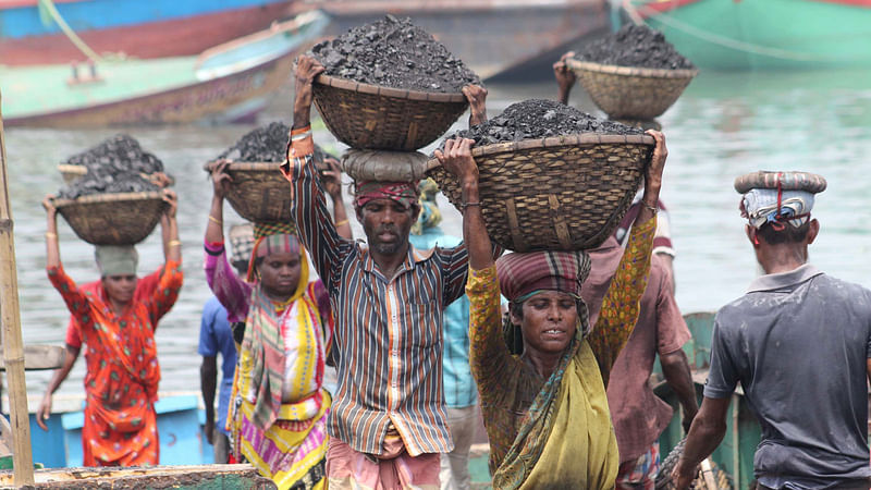 Labourers unload coal from a cargo vehicle