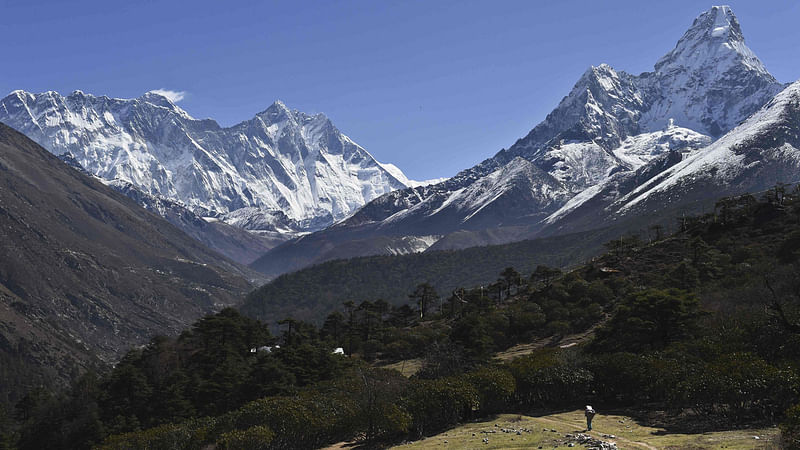 In this photograph taken on April 20, 2015, a Nepalese porter carries goods along a pathway in the Himalayas, with Mount Everest on the left, in the village of Tembuche in the Khumbu region of northeastern Nepal.