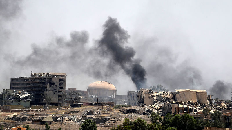 Smoke billows in a neighbourhood of west Mosul’s near Al-Shifa hospital (L) during ongoing battles between Iraqi forces to retake the city from Islamic State (IS) group fighters.