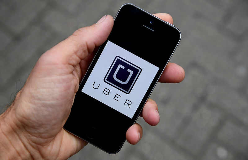 A photo illustration shows the Uber app logo displayed on a mobile telephone, as it is held up for a posed photograph in central London.