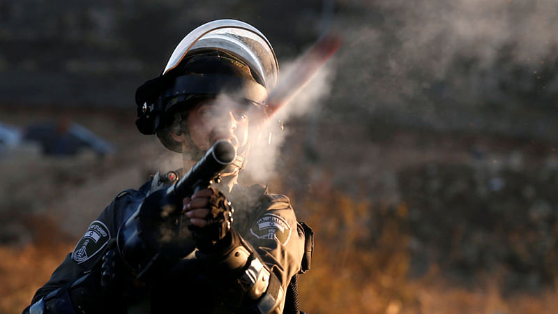 A member of Israeli troops fires a tear gas shell during clashes as Palestinians call for a `day of rage` in response to US president Donald Trump`s recognition of Jerusalem as Israel`s capital, near the border with Israel in the east of Gaza City 8 December, 2017