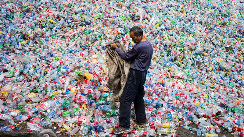 This file photo taken on 17 September 2015 shows a Chinese labourer sorting out plastic bottles for recycling in Dong Xiao Kou village, on the outskirt of Beijing.