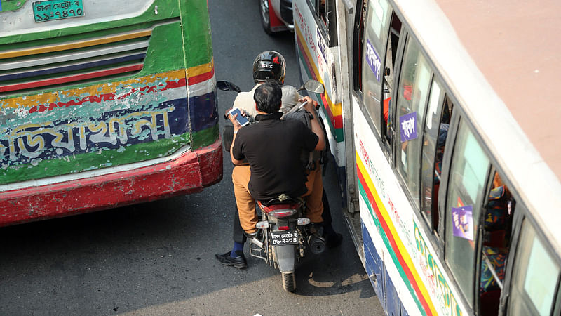 A motorbike driver tries to rush through the narrow gap between two buses near Shahbagh intersection in Dhaka on 5 April