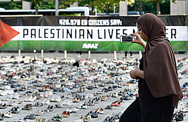 A woman takes a picture of an installation set up by a global civic organization Avaaz ahead of the EU council meeting in Brussels on 28 May, 2018. 4500 shoes representing every life lost in the Israel-Palestine conflict since 2009 have been displayed ahead of the EU Foreign ministers meeting.