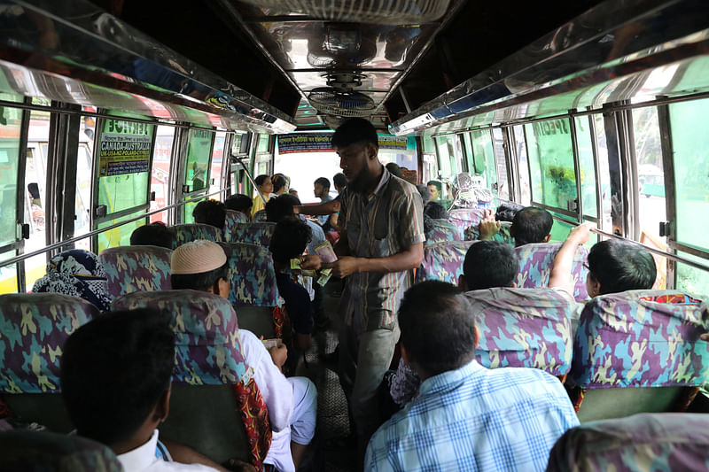 A driver`s assistant collects fare from passengers of a bus in Dhaka