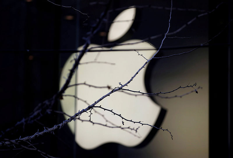 An Apple company logo is seen behind tree branches outside an Apple store in Beijing, China on 14 December 2018.